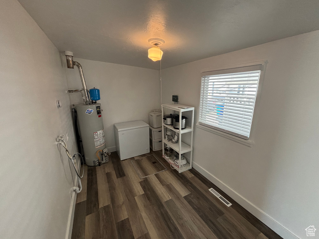 Laundry area with dark wood finished floors, gas water heater, baseboards, and visible vents