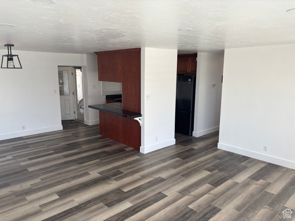 Unfurnished living room with baseboards and dark wood-style flooring