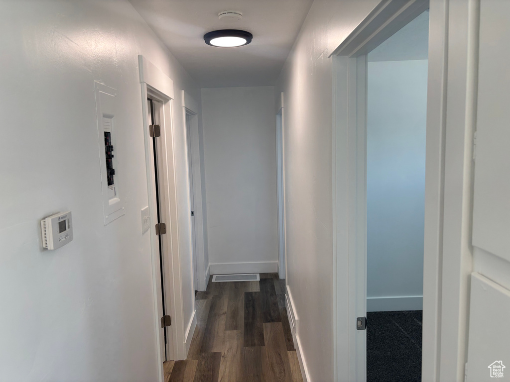 Corridor featuring baseboards and dark wood-type flooring