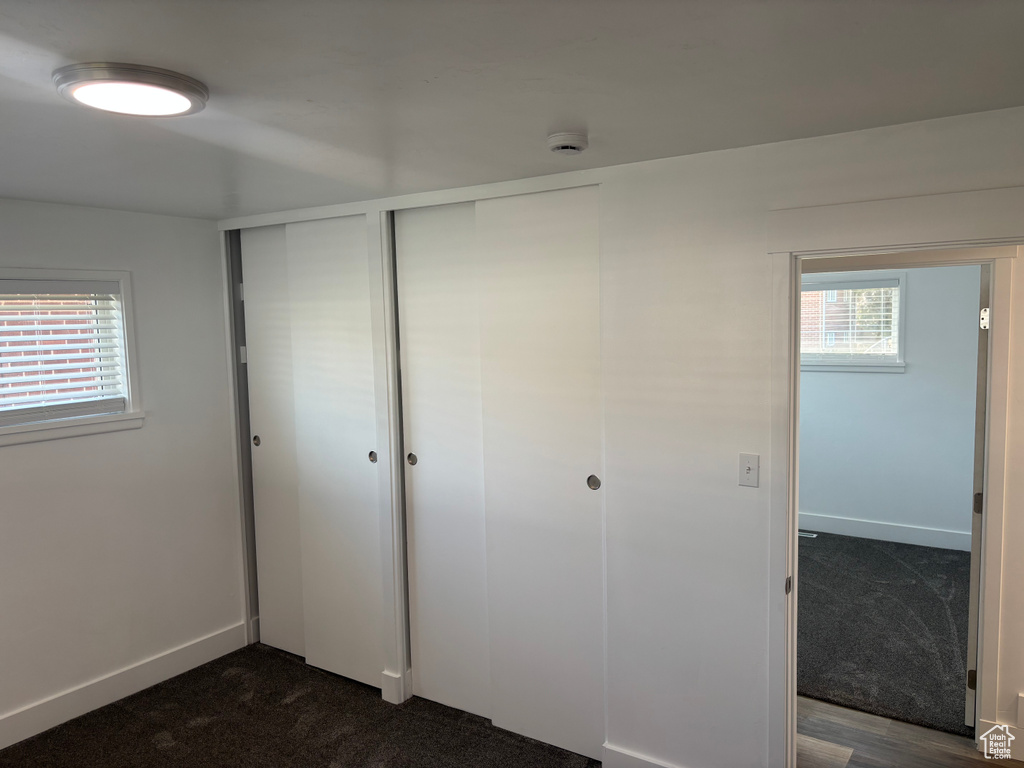 Unfurnished bedroom with baseboards, a closet, and dark carpet