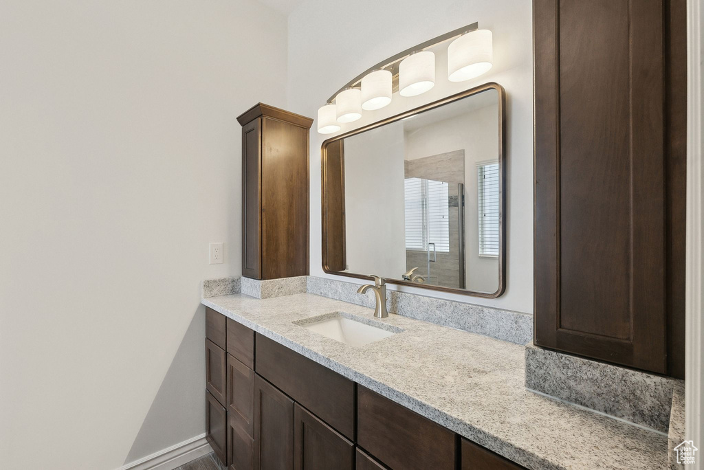 Full bathroom with vanity, a shower with door, and baseboards