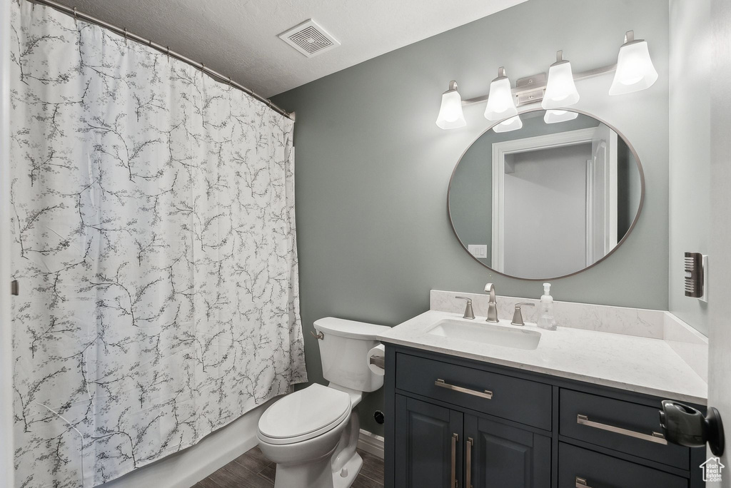 Full bath with visible vents, toilet, vanity, and wood finished floors