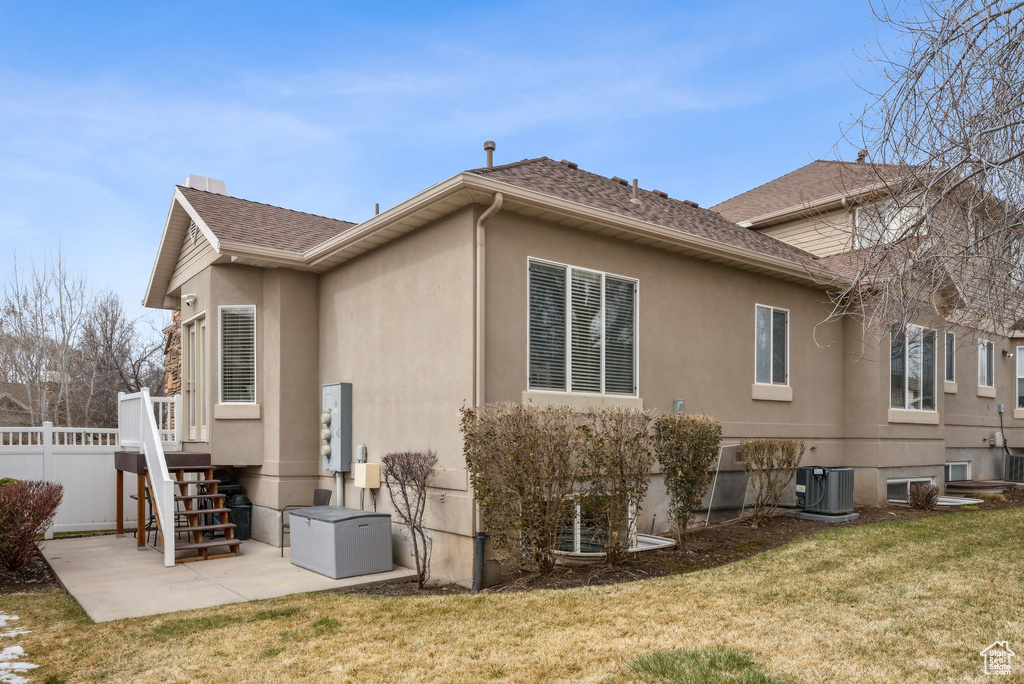 Back of house featuring a shingled roof, fence, central AC, a yard, and a patio area