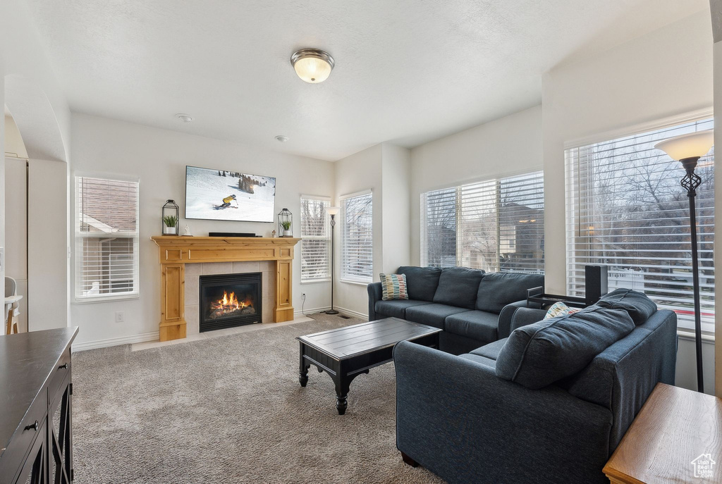 Carpeted living room with baseboards and a tile fireplace