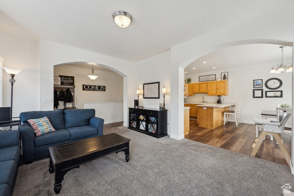 Living area with baseboards, recessed lighting, arched walkways, and dark colored carpet