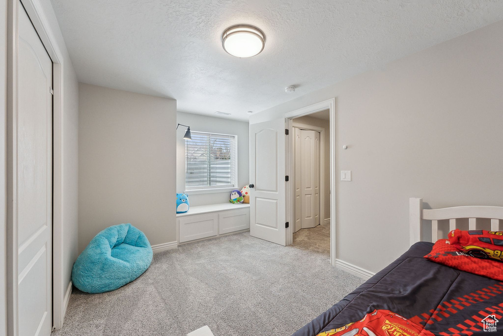 Bedroom featuring baseboards, a textured ceiling, and light colored carpet