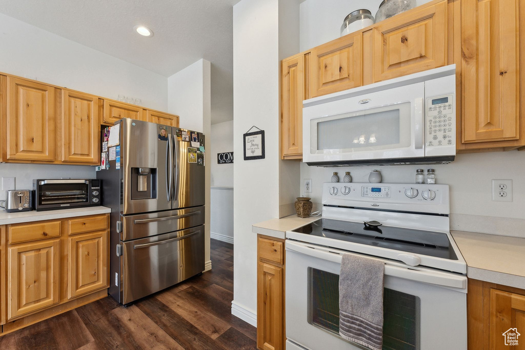 Kitchen with light countertops, recessed lighting, white appliances, dark wood-type flooring, and a toaster