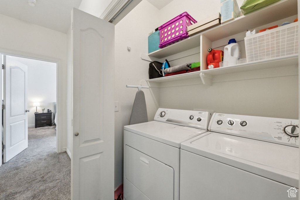 Laundry room with light carpet, baseboards, washer and dryer, and laundry area