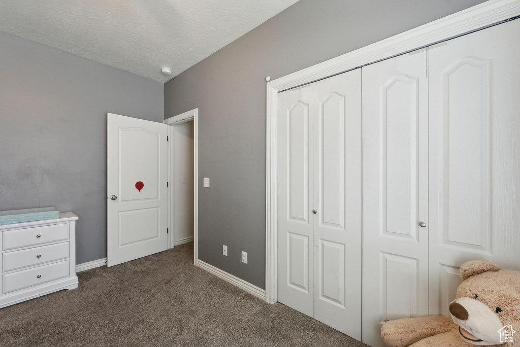 Bedroom with baseboards, a closet, dark colored carpet, and a textured ceiling