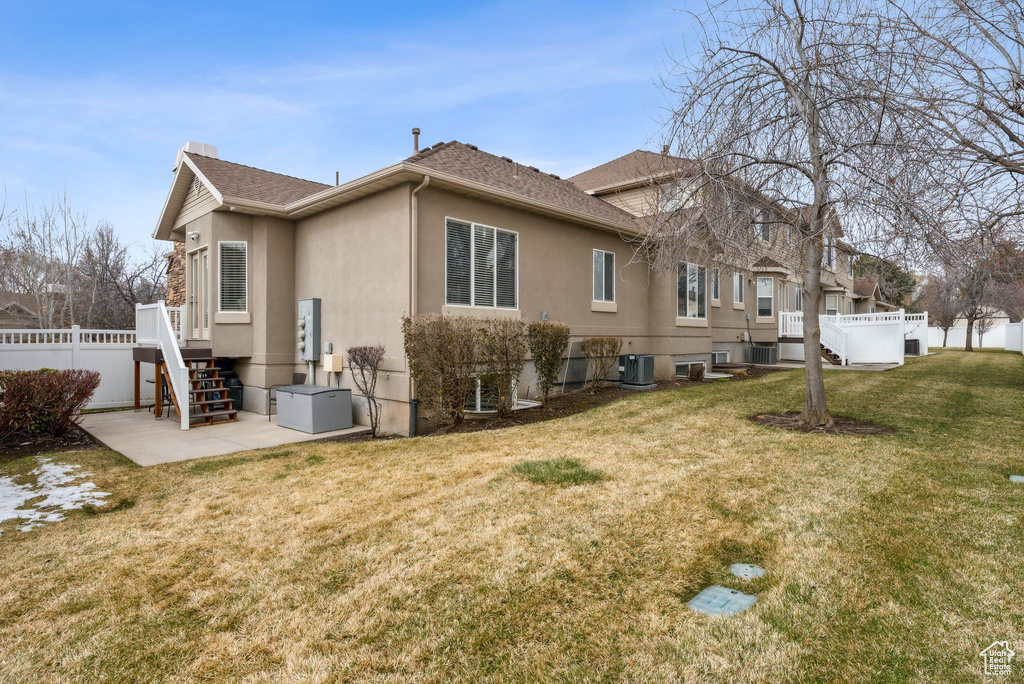 Back of property with fence, central AC unit, stucco siding, a yard, and a patio area