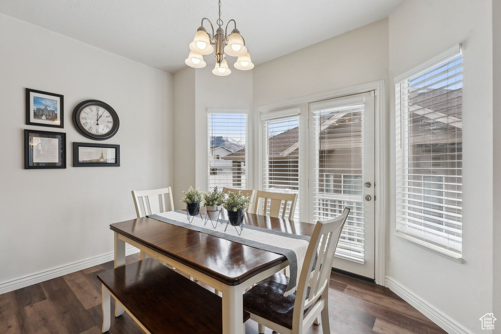 Dining area featuring dark wood finished floors, baseboards, and a notable chandelier