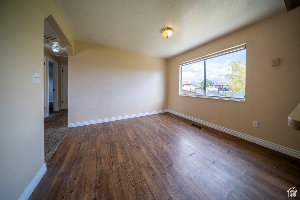 Unfurnished room featuring baseboards, visible vents, and dark wood-type flooring
