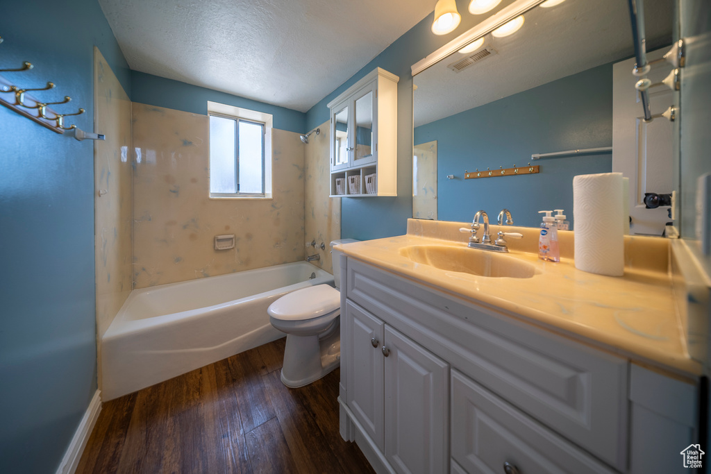 Bathroom with visible vents, vanity, wood finished floors, toilet, and bathtub / shower combination