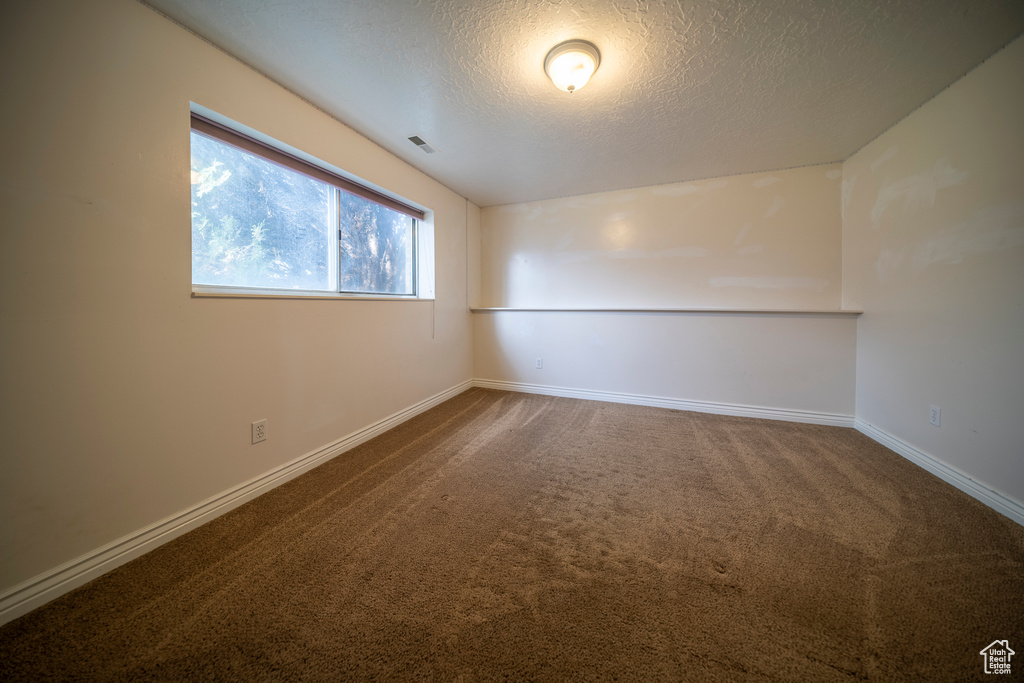 Carpeted empty room with a textured ceiling, visible vents, and baseboards