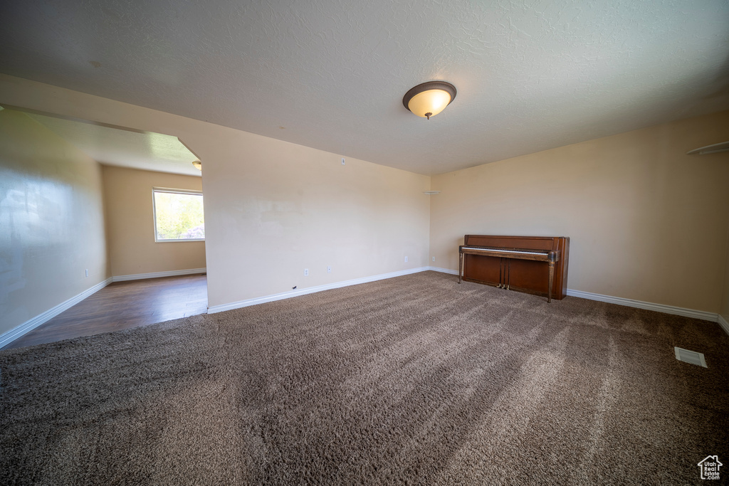 Unfurnished room with baseboards, carpet flooring, and arched walkways