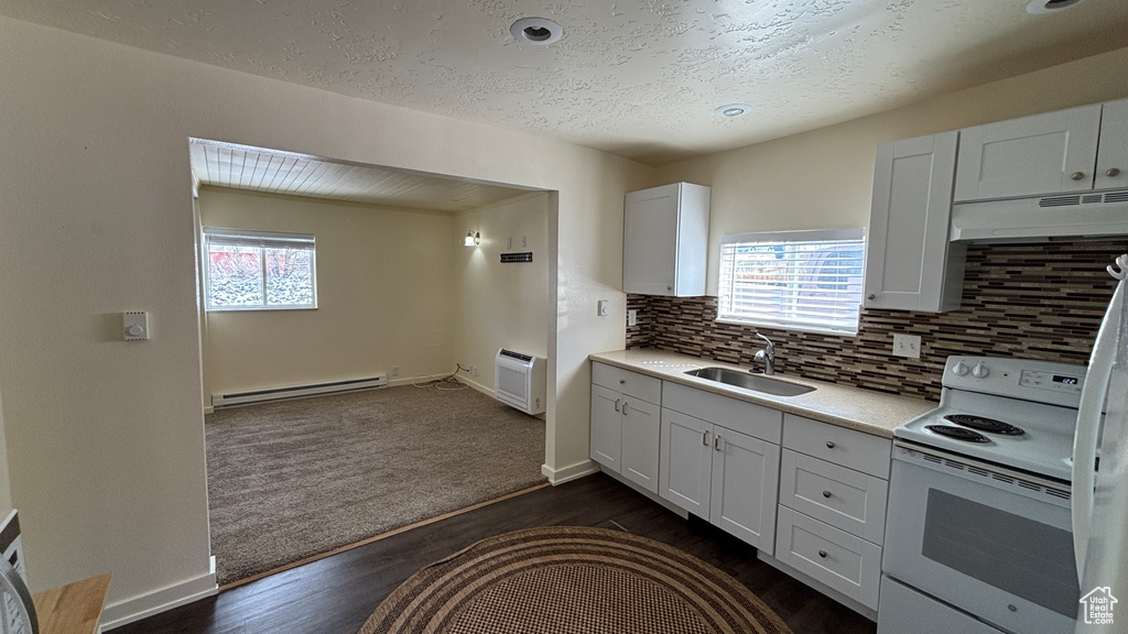 Kitchen with light countertops, under cabinet range hood, a sink, a baseboard heating unit, and white range with electric stovetop