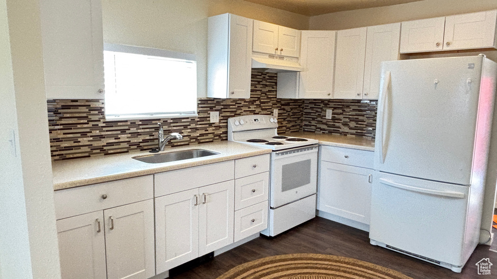 Kitchen with tasteful backsplash, white appliances, under cabinet range hood, a sink, and white cabinets