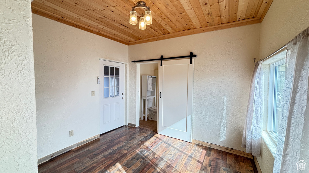 Unfurnished bedroom with a barn door, a textured wall, hardwood / wood-style floors, and wood ceiling