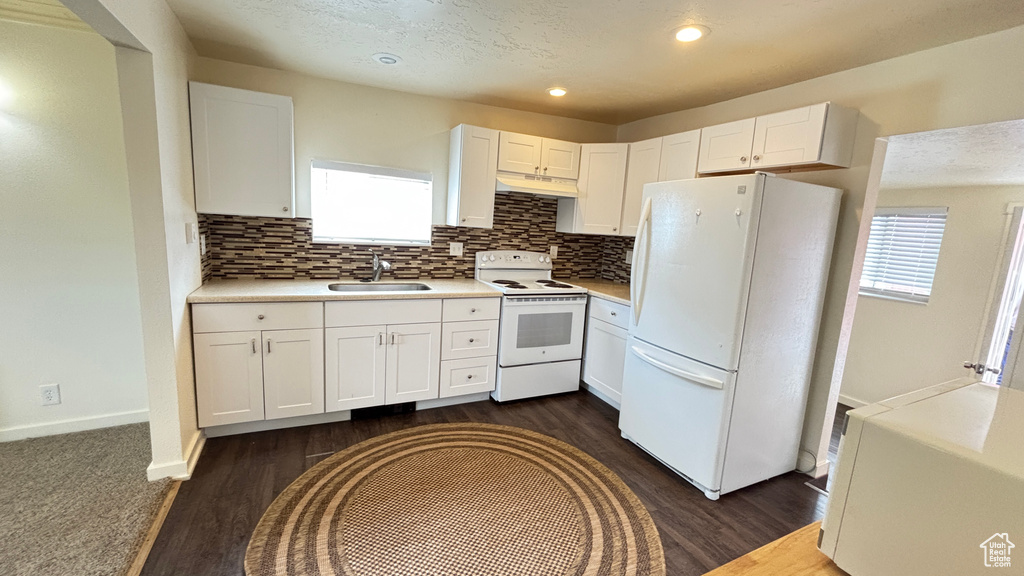 Kitchen featuring white cabinets, plenty of natural light, tasteful backsplash, and white appliances