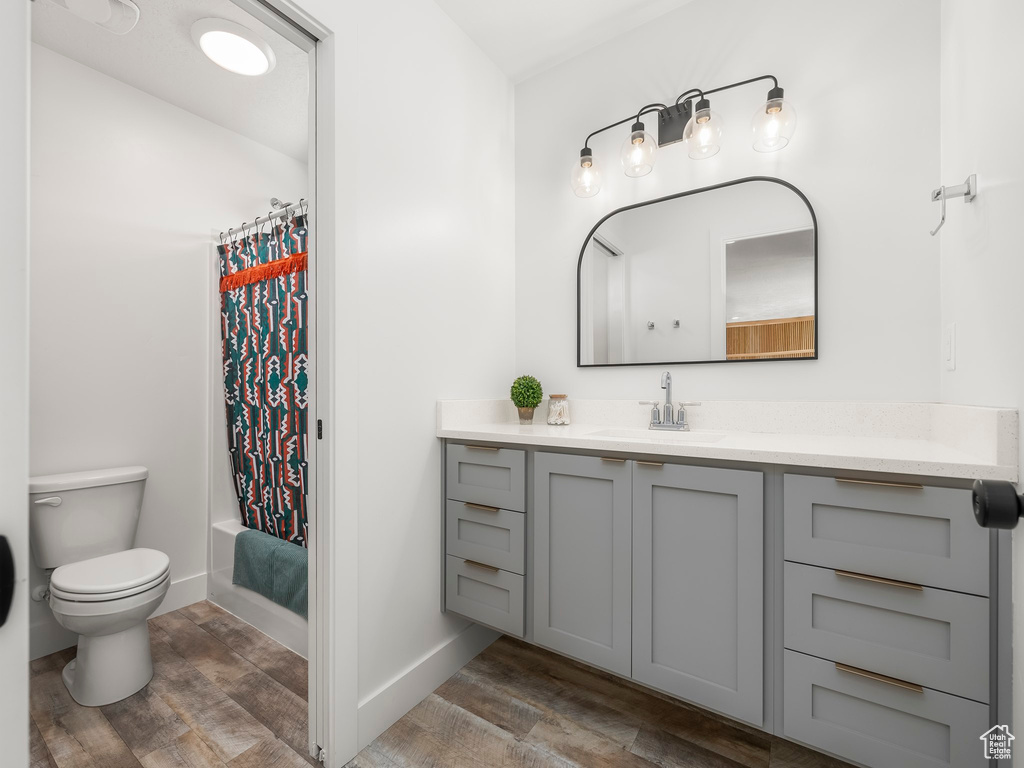Full bath featuring baseboards, toilet, vanity, and wood finished floors