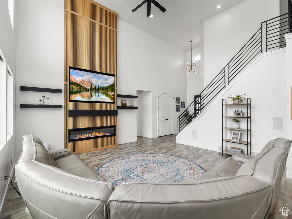 Living room with a towering ceiling, wood finished floors, stairway, and a ceiling fan