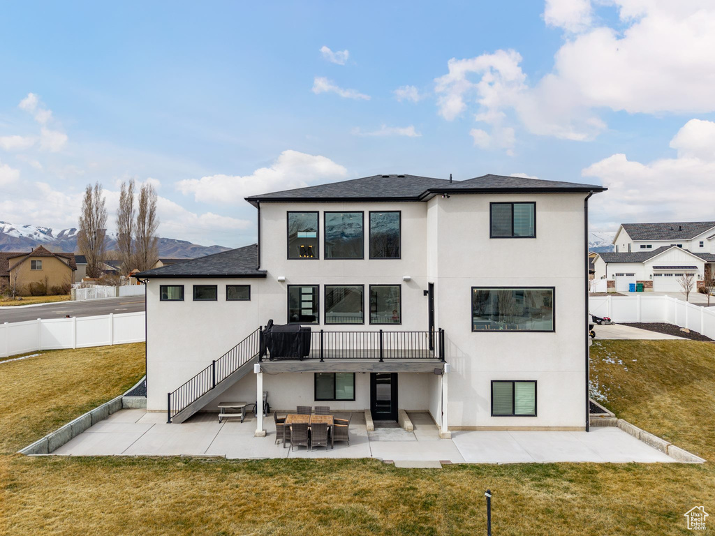 Rear view of property with a fenced backyard, a lawn, stucco siding, and a patio area