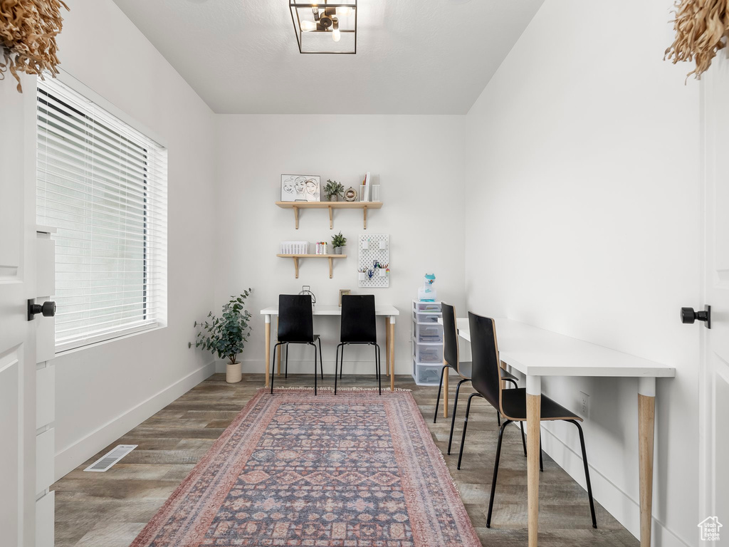 Home office with baseboards, visible vents, and wood finished floors
