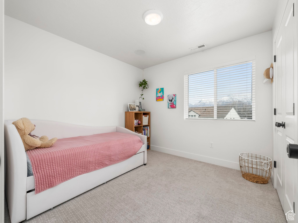 Carpeted bedroom featuring baseboards and visible vents