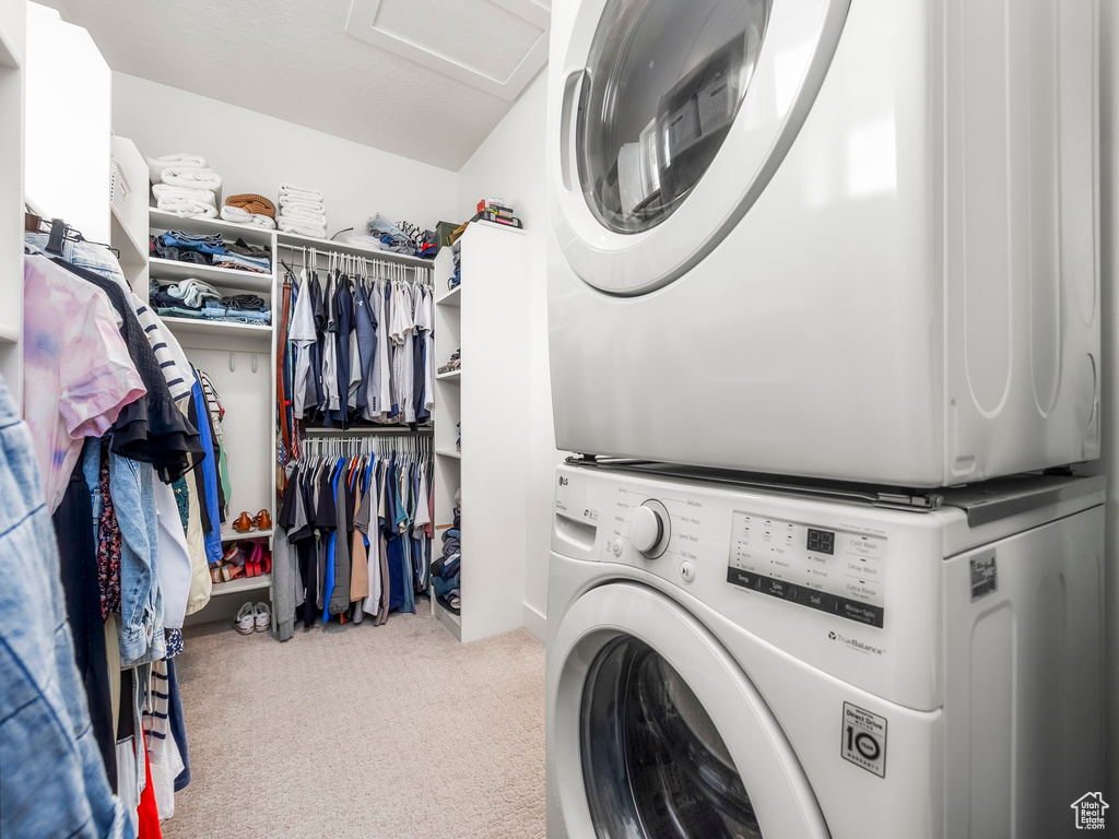 Laundry room featuring attic access, carpet floors, stacked washing maching and dryer, and laundry area