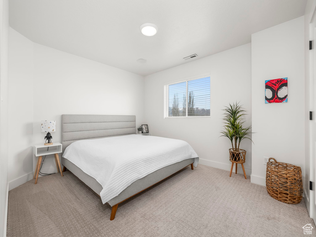 Carpeted bedroom featuring baseboards and visible vents