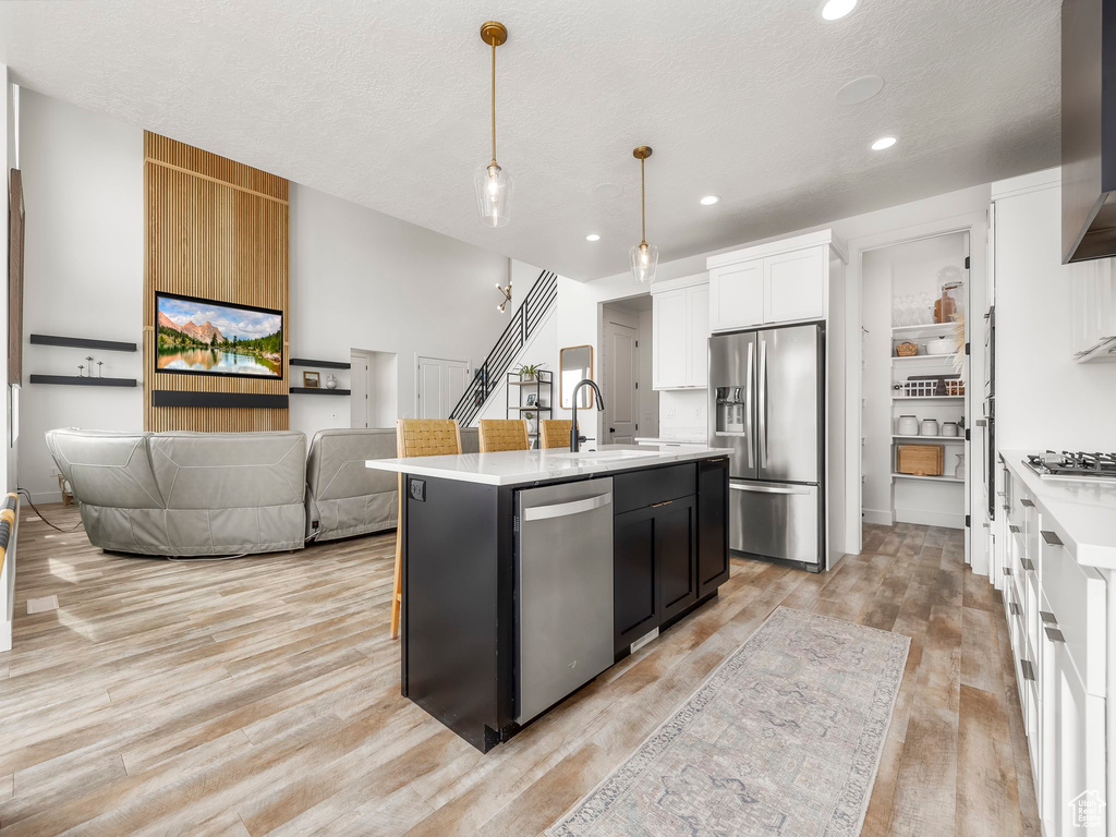 Kitchen with a sink, light countertops, light wood-style flooring, and appliances with stainless steel finishes
