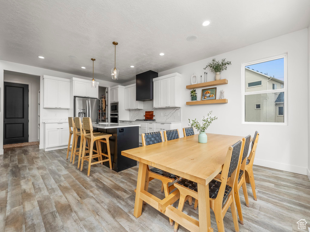 Dining area with baseboards, a textured ceiling, recessed lighting, and light wood finished floors