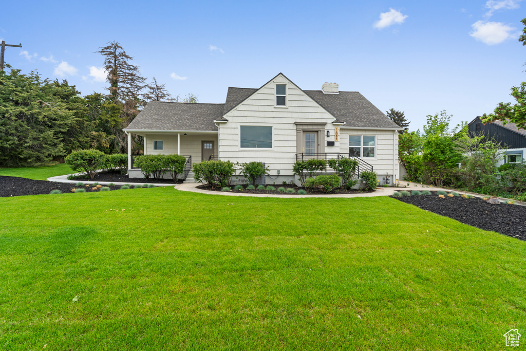 Bungalow-style house with a front lawn, roof with shingles, and a chimney