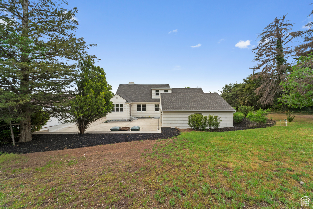 Rear view of house with a lawn, a chimney, and a patio