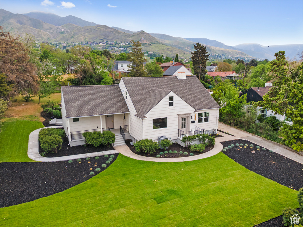 View of front facade with a front yard, roof with shingles, and a mountain view