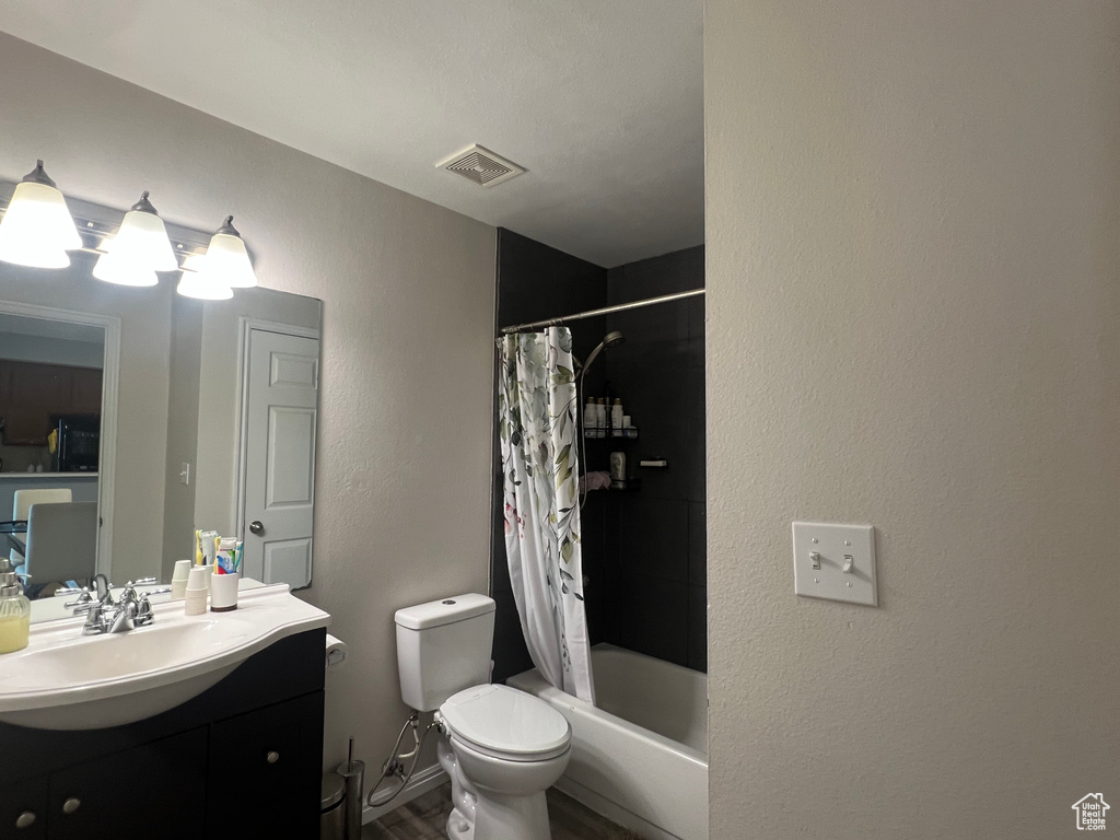 Full bathroom featuring visible vents, toilet, wood finished floors, vanity, and shower / bathtub combination with curtain