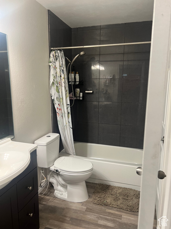 Bathroom with toilet, wood finished floors, vanity, and shower / bath combination with curtain
