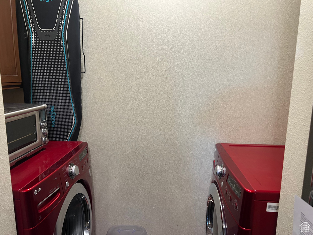 Clothes washing area with laundry area, a textured wall, and separate washer and dryer
