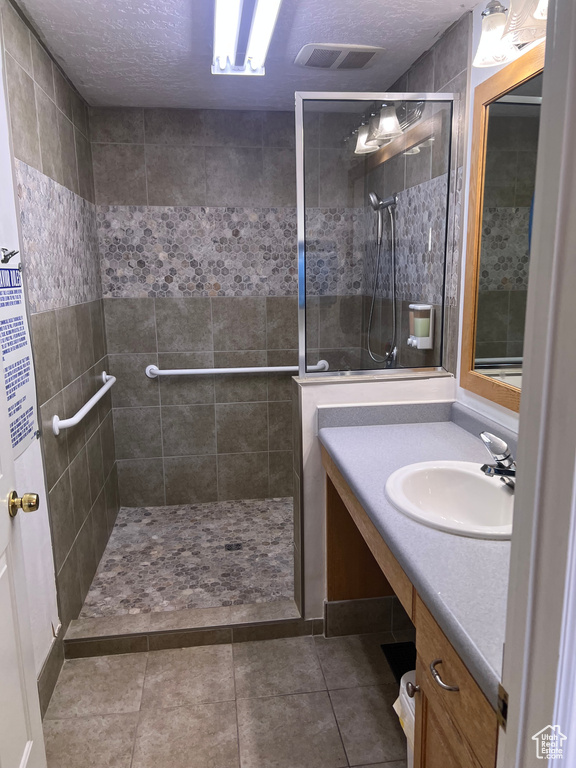 Bathroom featuring visible vents, a walk in shower, vanity, and a textured ceiling