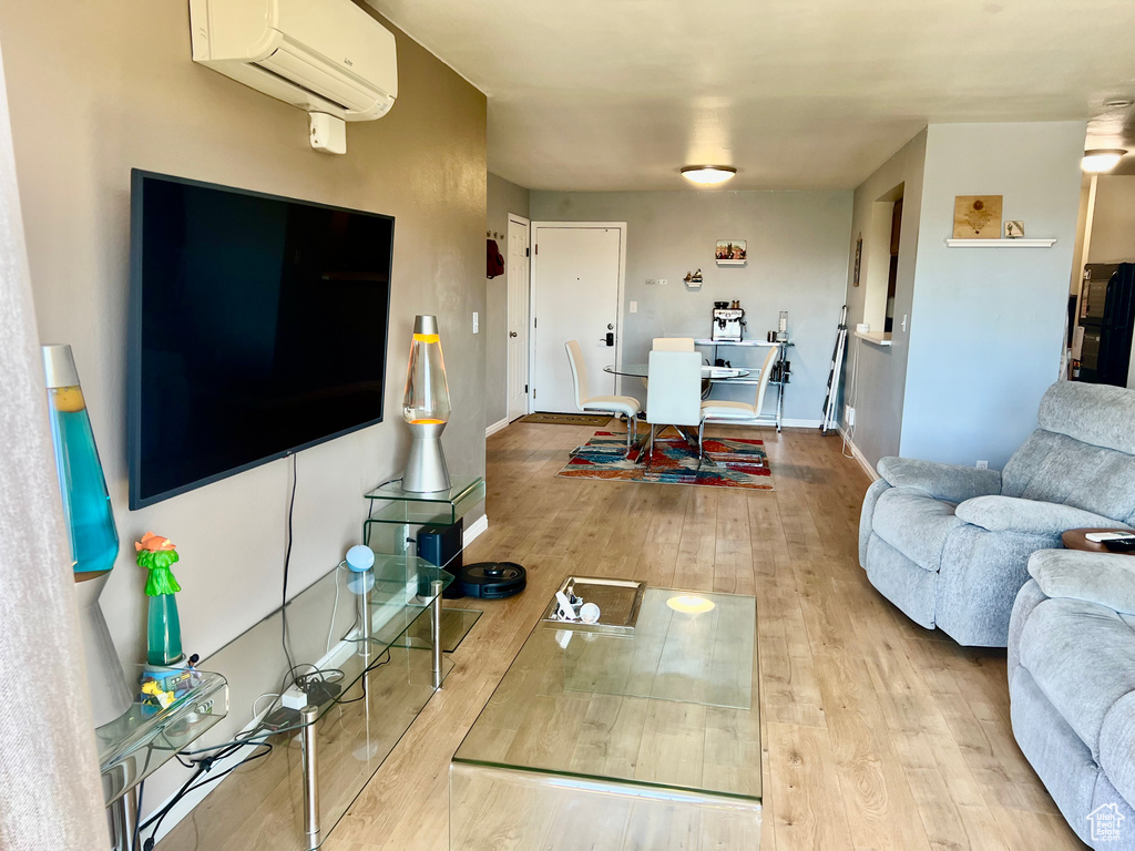 Living room featuring wood-type flooring, a wall mounted AC, and baseboards