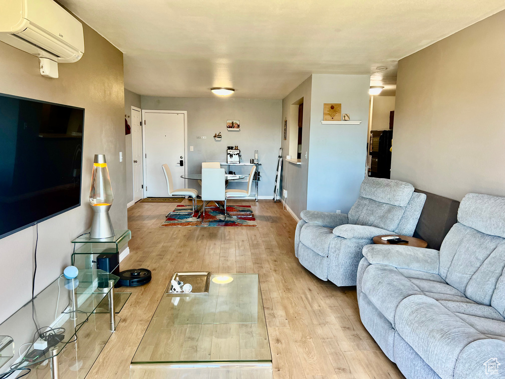 Living room with baseboards, an AC wall unit, and hardwood / wood-style flooring