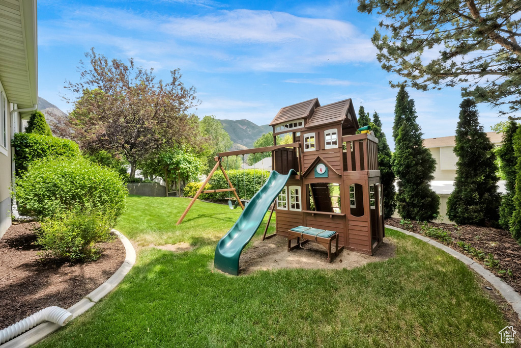 View of playground with a mountain view and a yard