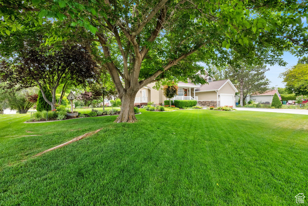 View of front of house featuring a garage, a front lawn, concrete driveway, and stone siding