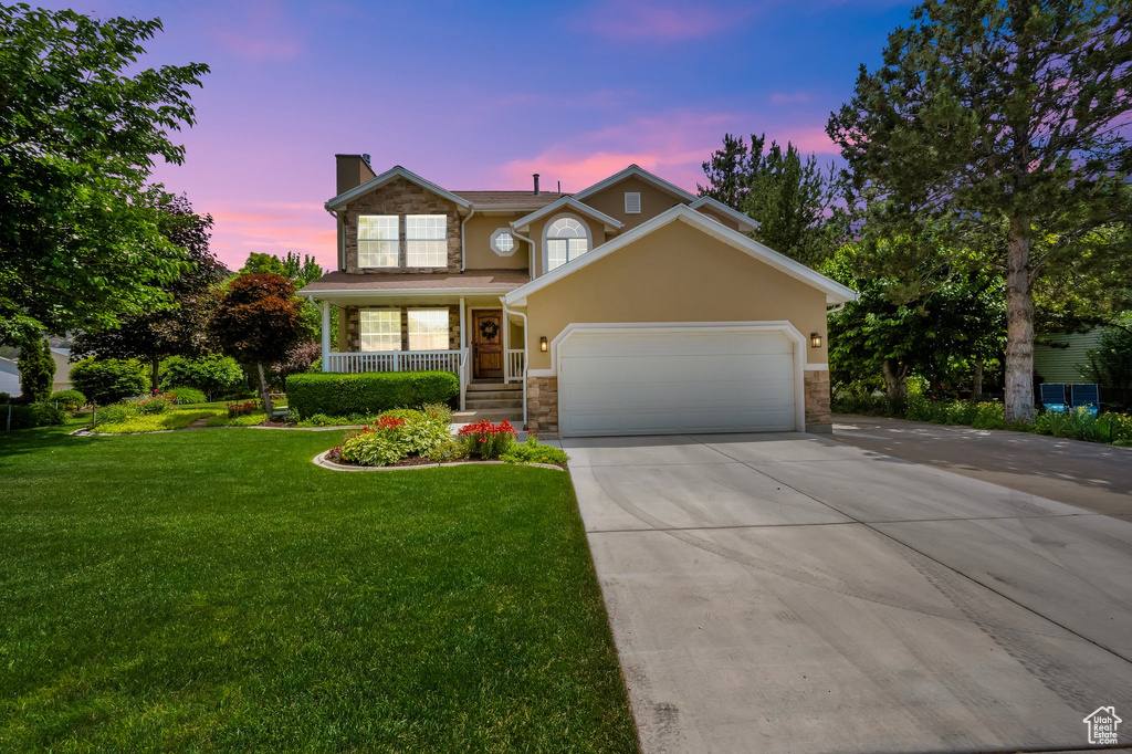 Traditional-style house with a chimney, stone siding, a garage, concrete driveway, and a porch