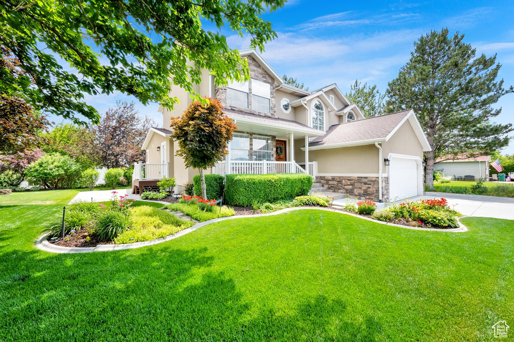 Traditional-style home with stucco siding, stone siding, a porch, concrete driveway, and a garage