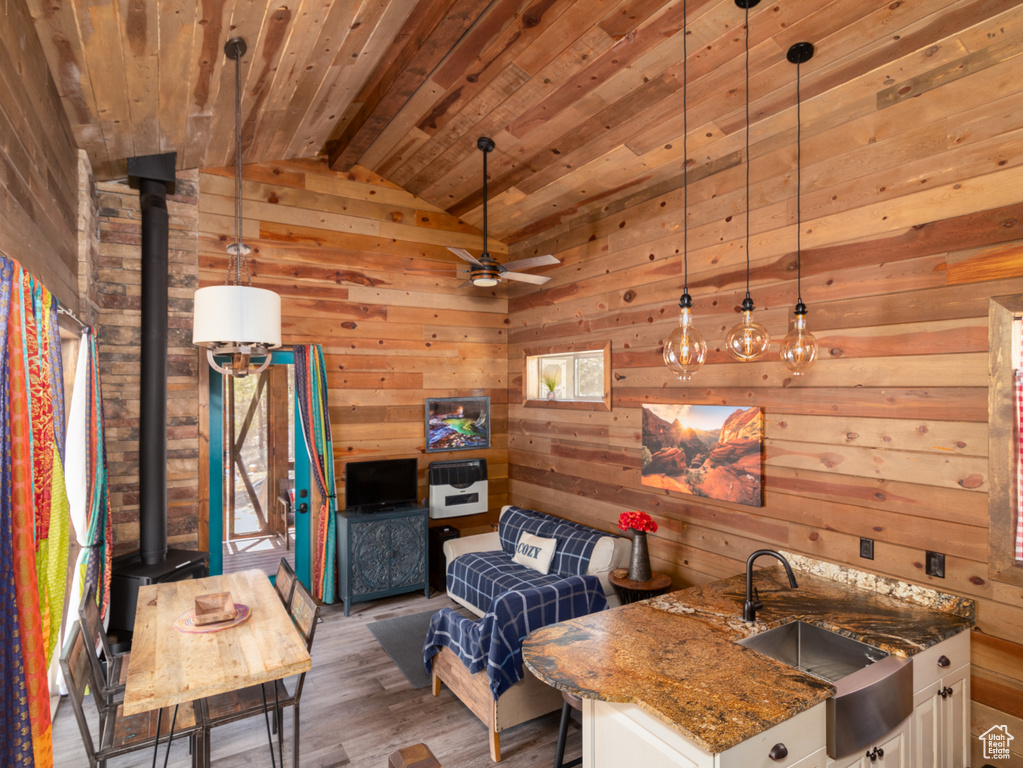 Kitchen featuring dark stone countertops, a sink, a wood stove, and wood ceiling