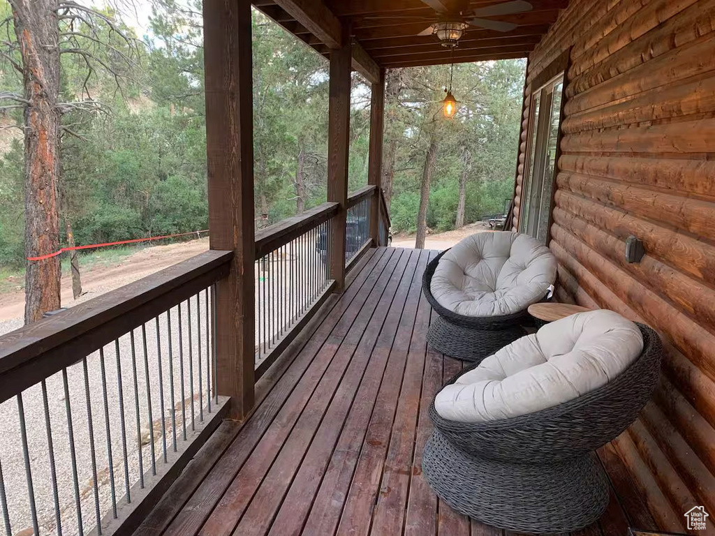Deck featuring a view of trees and ceiling fan