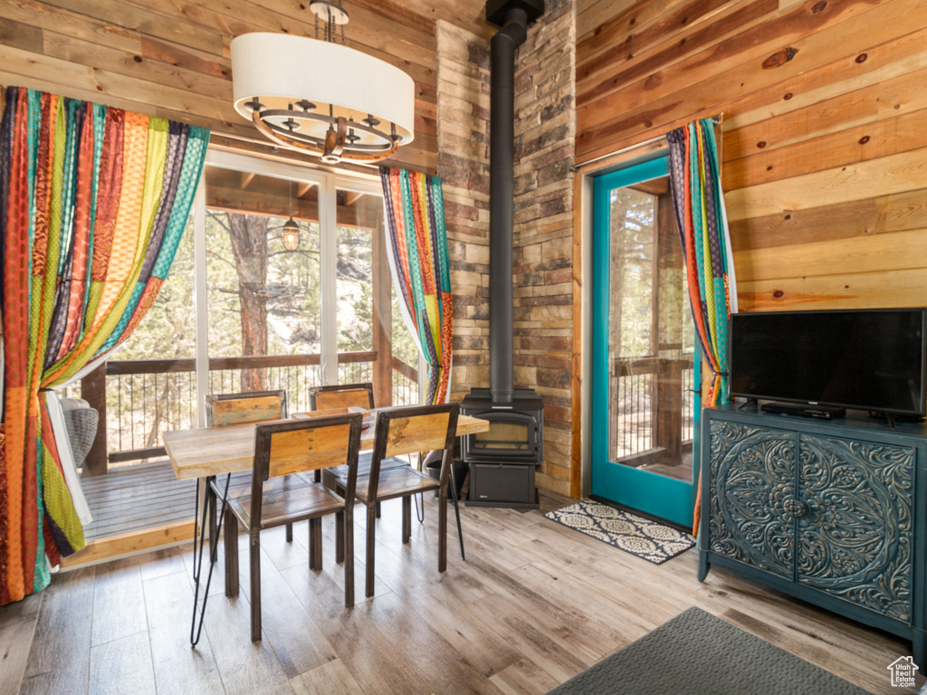 Dining space with a wealth of natural light, wood finished floors, a wood stove, and wooden walls