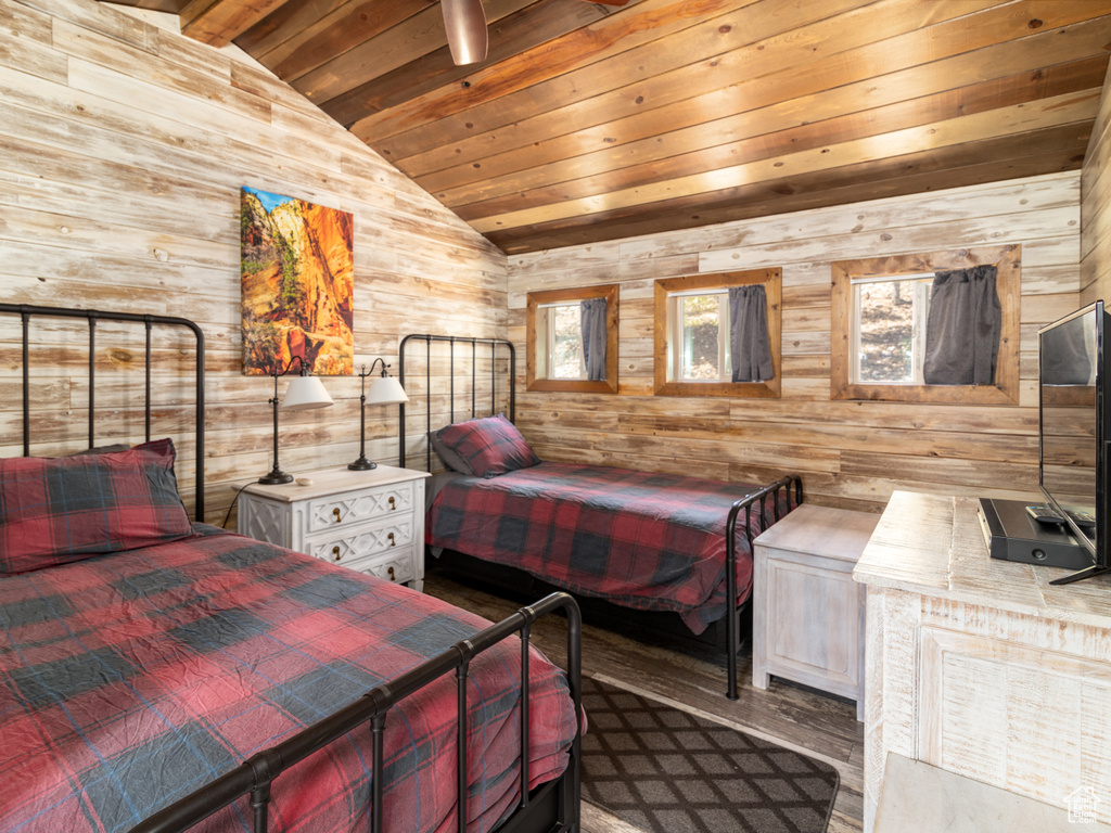 Bedroom with lofted ceiling, wood finished floors, wooden ceiling, and wood walls