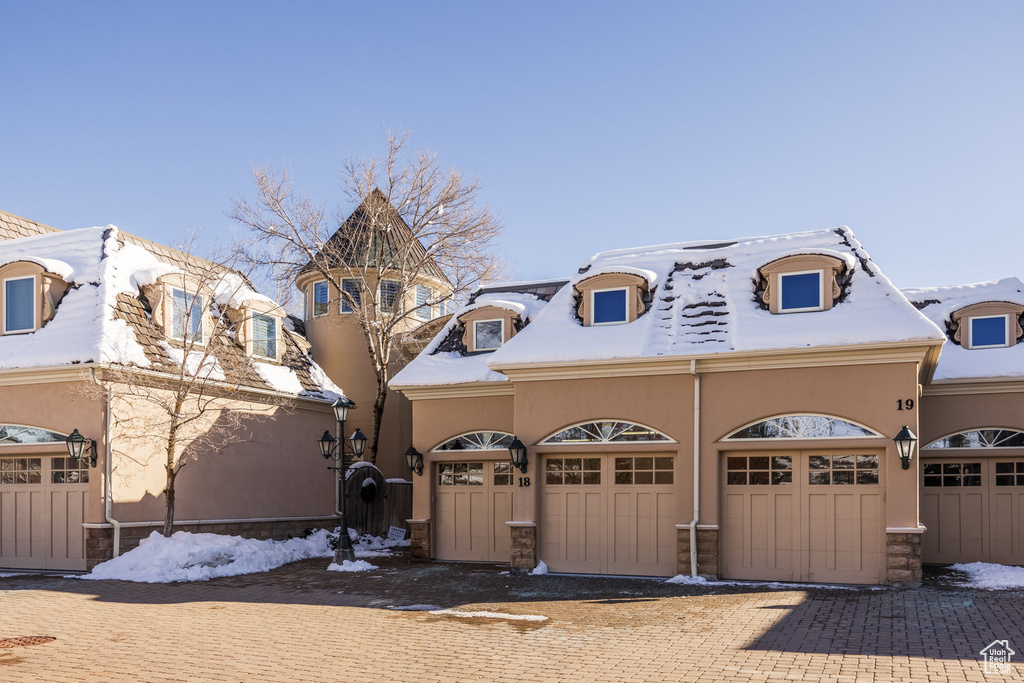 View of front facade featuring a garage, decorative driveway, and stucco siding